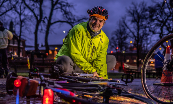 A man putting lights on his bike at dusk