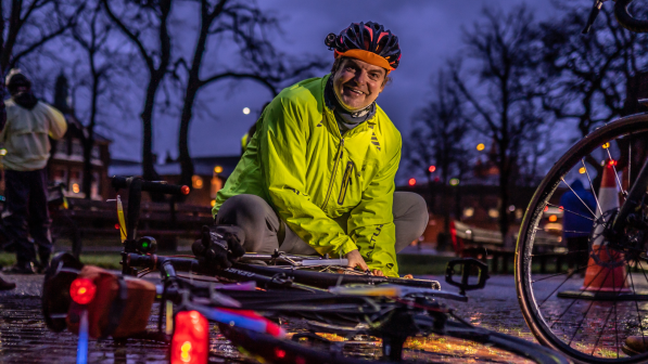 A man putting lights on his bike at dusk