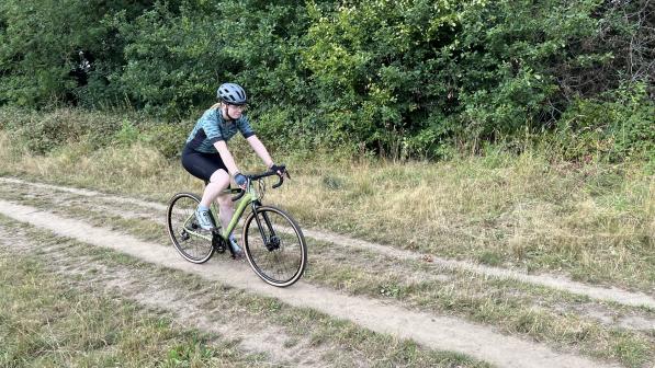 A woman cycles along a wooded track on an off-road bicycle