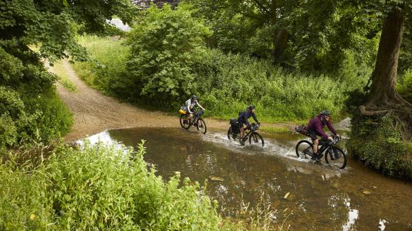 Three riders cross a ford on the Rebellion Way