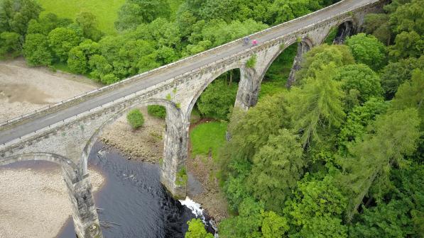 Two cyclists ride over a viaduct