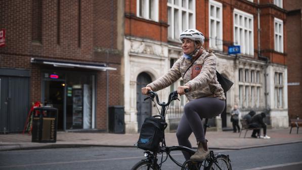 Women smiles as she pedals electric Brompton through city centre