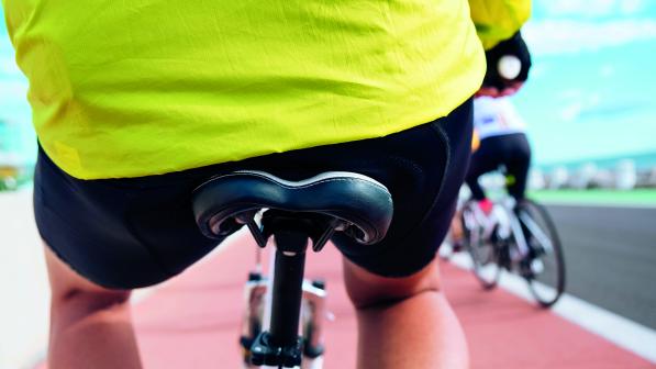 The rear view of a bicycle saddle on a bicycle, a man sits on the saddle