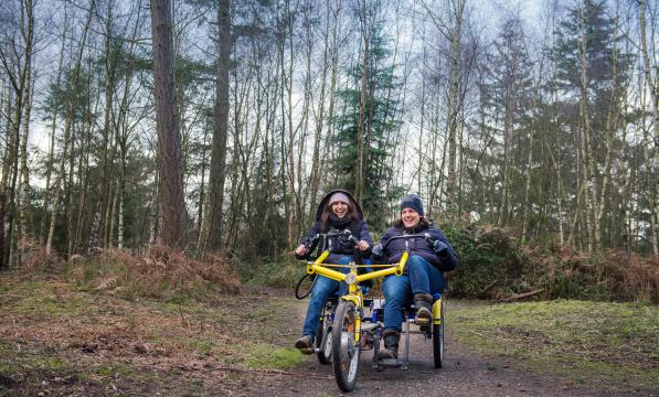 two women riding a twinbike tandem in the forest 