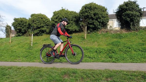 A man cycles along a cycle path on a red bicycle