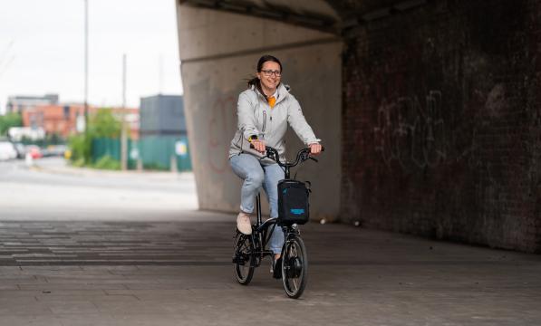 Woman pedals electric Brompton under building