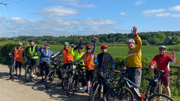 A group of cyclists waving at the camera