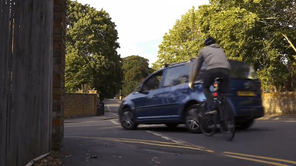 A car narrowly avoiding a cyclist while turning left.