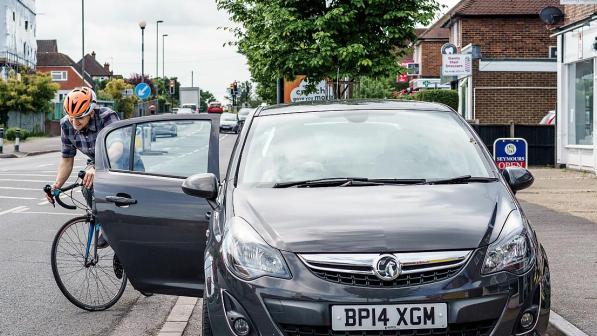 A cyclist narrow avoiding hitting an opening car door.