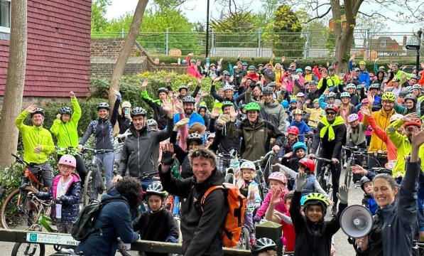 Large crowd of children and adults with bikes smiling and waving