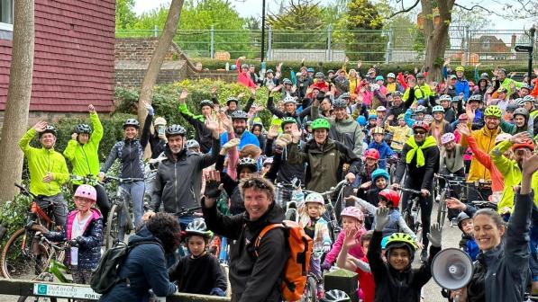 Large crowd of children and adults with bikes smiling and waving