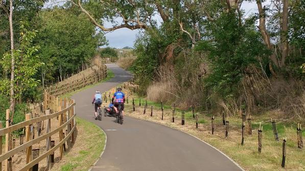 Two people cycle along a wide smooth tarmac cycle path