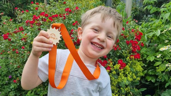Laurie holding up his medal while standing outside