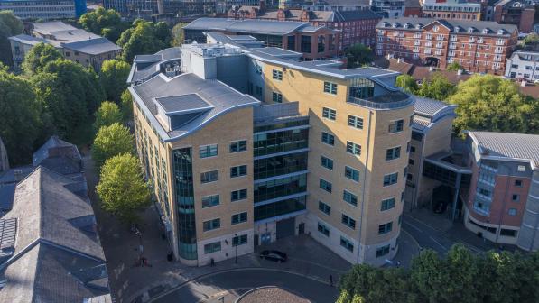 Aerial view of One Trinity Gardens, a modern multi-storey office building with a curved corner, located in central Newcastle near the Quayside, surrounded by trees and nearby buildings.