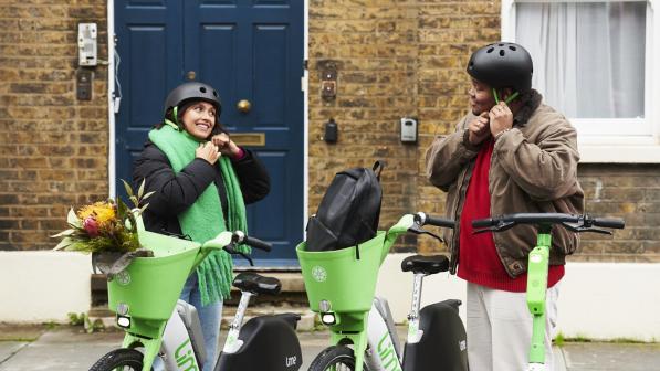 Two people putting on helmets standing next to Lime bikes