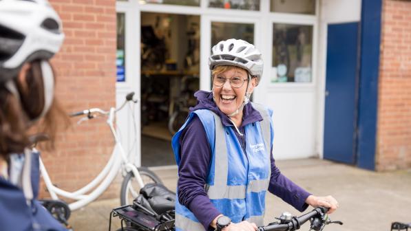 Woman smiling while standing over her bike wearing a helmet