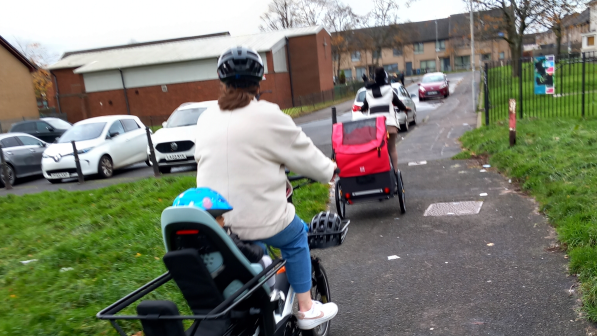 Families cycling on various cycle types on a path with greenery either side