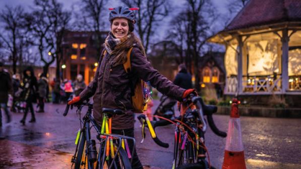 A cyclist attending a glow ride event.  Her bike is decorated with glow sticks. 