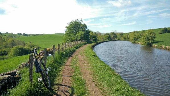 A unicycle on a towpath next to a canal in summer.
