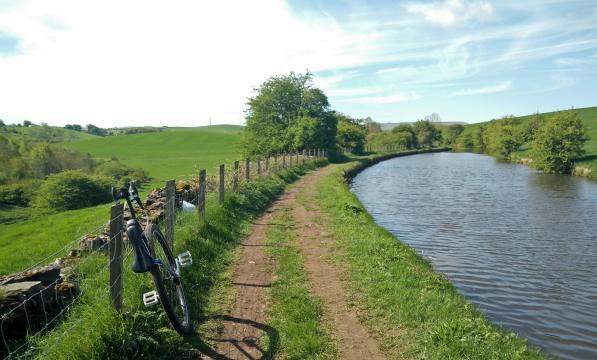 A unicycle on a towpath next to a canal in summer.