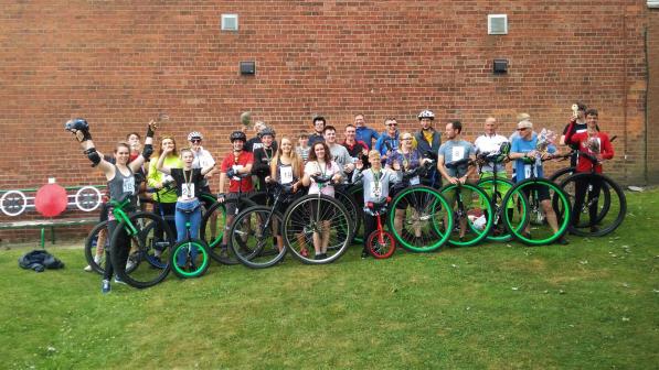 A large group of people standing by unicycles