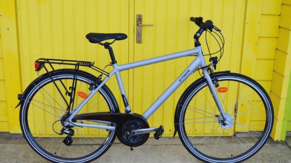 B’Twin Hoprider 300 City, a grey hybrid bike with flat bar, mudguards and rear rack