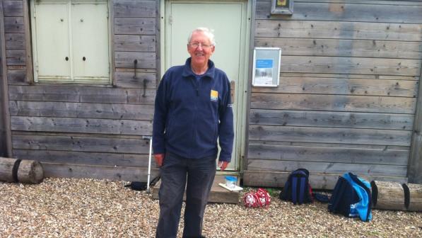 A man is standing in front of a shed