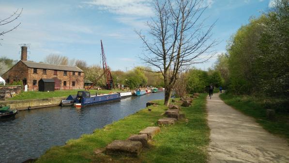 Unicyclists passing Thwaites Mill, alongside the Aire and Calder Navigation